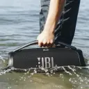 سماعة JBL Boombox 3 محمولة من المقبض وسط رذاذ الماء، صورة استخدام واقعي - كايرو فولت