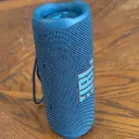 سماعة JBL Flip 6 باللون الأزرق واقفة رأسياً على طاولة خشبية - كايرو فولت