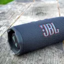 سماعة JBL Flip 7 سوداء موضوعة على طاولة خشبية قديمة في الخارج - كايرو فولت